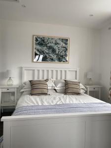 een witte slaapkamer met een groot wit bed met kussens bij The Crows Nest - Sheringham in Sheringham