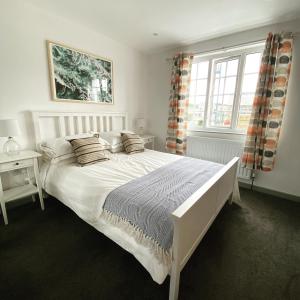 a bedroom with a white bed and a window at The Crows Nest - Sheringham in Sheringham