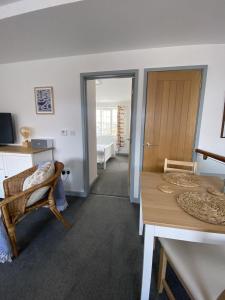 a living room with a table and a room with a tub at The Crows Nest - Sheringham in Sheringham