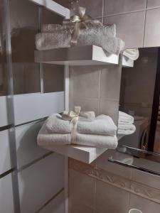 - une salle de bains pourvue de serviettes blanches sur une étagère dans l'établissement La casa di Sarah, à Syracuse