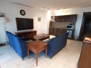sala de estar con sillas azules, mesa y TV en Durrah Beach Apartment en Durat  Alarous