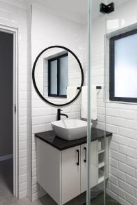 a white bathroom with a sink and a mirror at Santos Seaview Apartment in Mossel Bay