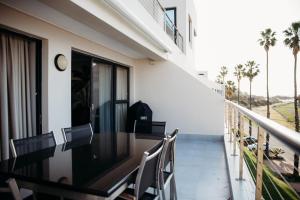 a balcony with a table and chairs and palm trees at Santos Seaview Apartment in Mossel Bay