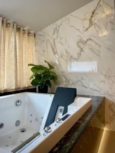 La salle de bains est pourvue d'une baignoire blanche et d'une plante. dans l'établissement La Croisée des Sens, à Croisy-sur-Eure