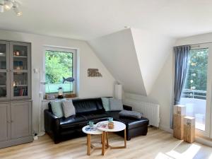 ein Wohnzimmer mit einer schwarzen Ledercouch und einem Tisch in der Unterkunft FeWo FriesenSPOt in Sankt Peter-Ording