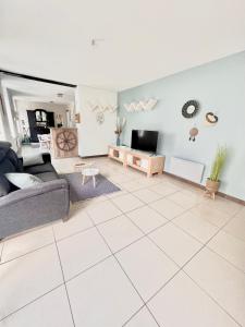 a living room with a couch and a tv at Agréable maison de ville cosy de 122m² + extérieur in Wattrelos