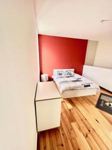 małą sypialnię z łóżkiem i czerwoną ścianą w obiekcie Agréable maison de ville cosy de 122m² + extérieur w mieście Wattrelos
