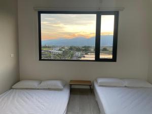 2 camas en una habitación con ventana grande en Tino House 全新開幕 質感包棟民宿 en Yilan City