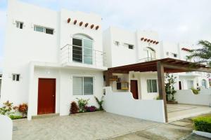 une maison blanche avec une porte rouge dans l'établissement Ecusuites Playas House III Resort Altamar 45Min GYE, à Playas