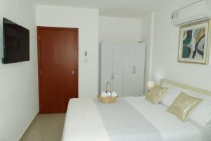 Un dormitorio con una cama blanca con una cesta. en Ecusuites Playas House III Resort Altamar 45Min GYE en Playas
