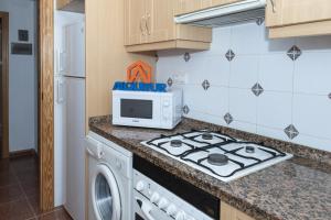 a kitchen with a stove and a microwave at Pleno Sol, 45 in Cullera