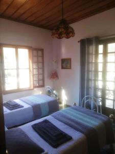 two beds in a room with two windows at Panoramic Views Home in Hydra, Greece in Hydra