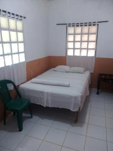 ein Schlafzimmer mit einem Bett und einem Stuhl sowie zwei Fenstern in der Unterkunft Amy's room in Bluefields