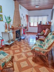 a living room with a fireplace and chairs at pousada helebastian in Campos do Jordão
