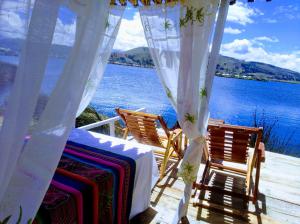 a table and chairs on a deck with a view of the water at Titicaca wasy lodge in Puno