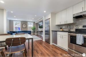 a kitchen with white cabinets and a table with chairs at J Miller Flats by Thatch in Boston