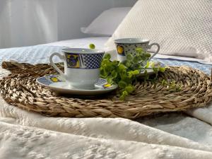 una bandeja con dos tazas y una planta en una cama en El mirador de María, en Alcalá del Júcar