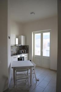 eine weiße Küche mit einem Tisch und einem Fenster in der Unterkunft La Neviera in Struda