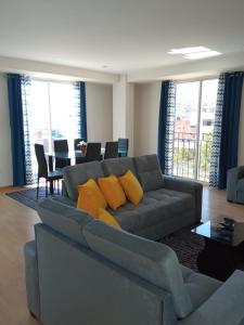 a living room with a gray couch with yellow pillows at Buena Vista Apartment in Cusco