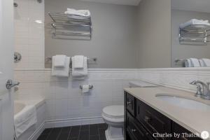 a white bathroom with a sink and a toilet at 94 Charles Street by Thatch in Boston