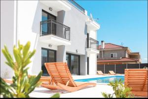 a villa with a swimming pool and two lawn chairs at Villa BO in Koprivno