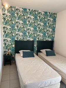 two beds in a room with a blue and white wallpaper at Villa du Golf Eden Parc in Lacanau-Océan