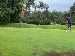 un homme joue au golf sur un parcours dans l'établissement Villa du Golf Eden Parc, à Lacanau-Océan