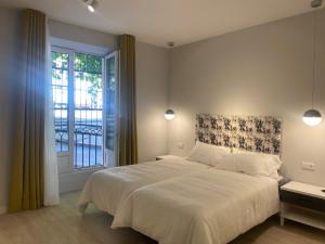 a bedroom with a large white bed with a window at APARTAMENTOS LA FLORA BURGOS todos con aire acondicionado y ascensor in Burgos