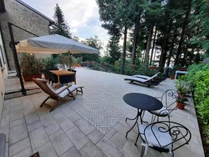 eine Terrasse mit einem Tisch, Stühlen und einem Sonnenschirm in der Unterkunft BELLA TUSCANY - Residence in Cireglio