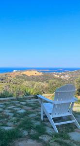 una sedia blu seduta per terra con l'oceano sullo sfondo di Gorgeous private Villa with sea view! ad Andro