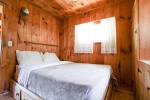a bedroom with a bed in a wooden cabin at Adirondack Waterfront Cabin Upper Hudson Tributary in Lake Luzerne