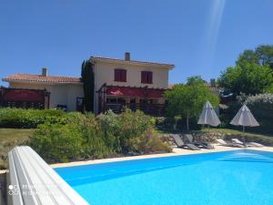 a villa with a swimming pool in front of a house at Le clos mirélie in Gaujac