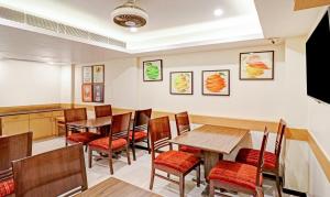 una sala da pranzo con tavoli e sedie in legno di Treebo Trend Galaxy Rooms a Nuova Delhi