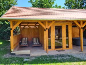 a wooden gazebo with two chairs and a roof at Cseresznyés Vendégház in Szomolya