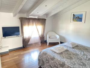sypialnia z łóżkiem, krzesłem i telewizorem w obiekcie Casa Alda w mieście La Spezia