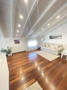 salon z białą kanapą i drewnianą podłogą w obiekcie Casa Alda w mieście La Spezia