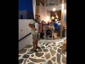 a man is holding an accordion in a restaurant at Studio Seagull - By Old Market Street - Naxos Town in Naxos Chora