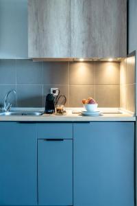 Heraclea Luxury Suites في نيا إيراكليا: مطبخ مع خزائن زرقاء ووعاء من الفواكه