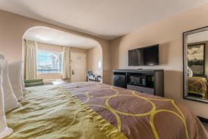 una camera d'albergo con un grande letto e una TV a schermo piatto di Super 8 by Wyndham Lake Charles Northeast a Lake Charles
