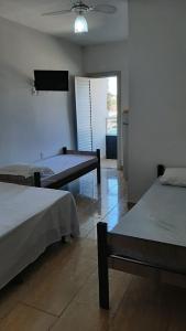 a bedroom with two beds and a flat screen tv at Pousada Campo Verde in Guarapari