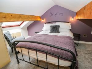 1 dormitorio con cama y pared púrpura en 19 The Village, en Holmfirth