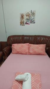 a bed with a brown leather headboard and pink pillows at ANI Apartments Banja Luka in Banja Luka