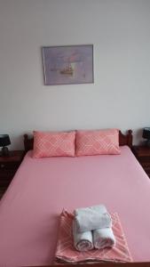 a pink bed with two towels sitting on it at ANI Apartments Banja Luka in Banja Luka