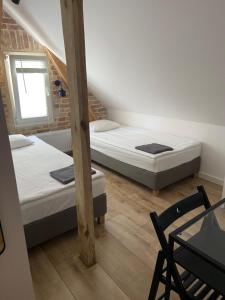 two beds in a room with a table and a chair at Hostel 19 Sopot in Sopot