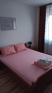 a bed with pink sheets and two towels on it at ANI Apartments Banja Luka in Banja Luka