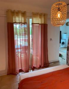 1 dormitorio con cortinas rojas y amarillas y lámpara de araña en Appartement cosy & calme en Rez de villa, en Saint-François