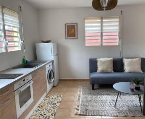 cocina y sala de estar con sofá y mesa en Appartement cosy & calme en Rez de villa en Saint-François