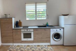 a kitchen with a refrigerator and a washing machine at Appartement cosy & calme en Rez de villa in Saint-François