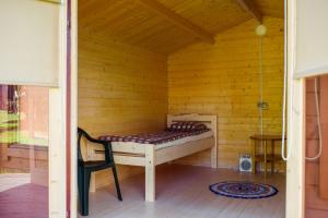 Ce lit se trouve dans une chambre en bois dotée d'une chaise. dans l'établissement Kivimaa Puhkemaja, à Tiidu