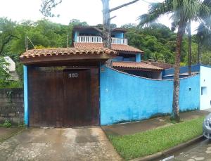 a blue house with a brown door with a balcony at Casa Azul in Caraguatatuba